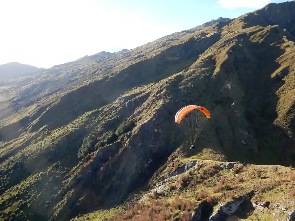 An orange wing against a steep brown hillside