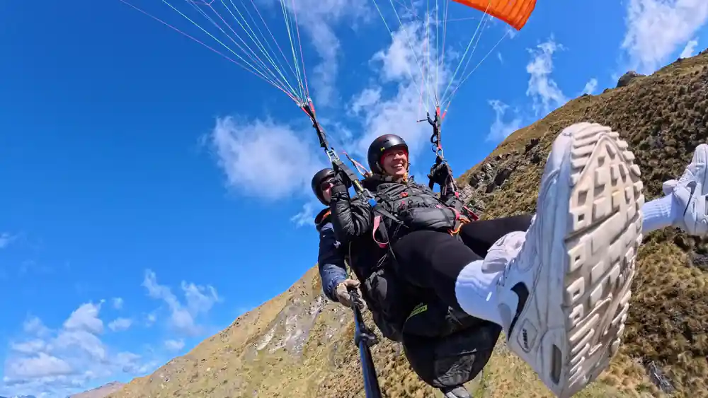 A tandem climbing past cloud above the hills